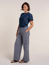 Load image into Gallery viewer, Woman wearing a blue shirt and checkered pants on a plain background
