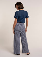 Load image into Gallery viewer, Woman wearing a blue shirt and checkered pants on a white background
